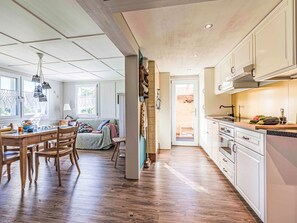 Eine geräumige Küche mit Holzboden, weißen Schränken und einem Essbereich mit Tisch und Stühlen.