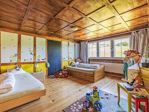 Ein Zimmer mit Holzboden, einem Bett, einem Fenster, einem Heizkörper und Spielzeug.