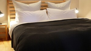Uma cama com cabeceira de madeira, travesseiros brancos e edredom preto.