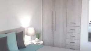 Ein Schlafzimmer mit Bett, Nachttisch mit Lampe und Kleiderschrank.
