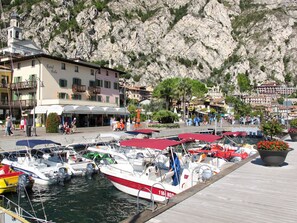 Un port de plaisance avec des bateaux amarrés, un hôtel appelé « Hotel Solo » en arrière-plan et une colline rocheuse.