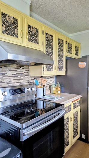 A kitchen with a stainless steel stove, a refrigerator, and patterned cabinets.