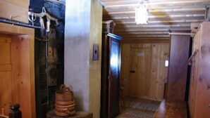 Un interior de fusta amb sòl, banc, armari i porta de fusta.