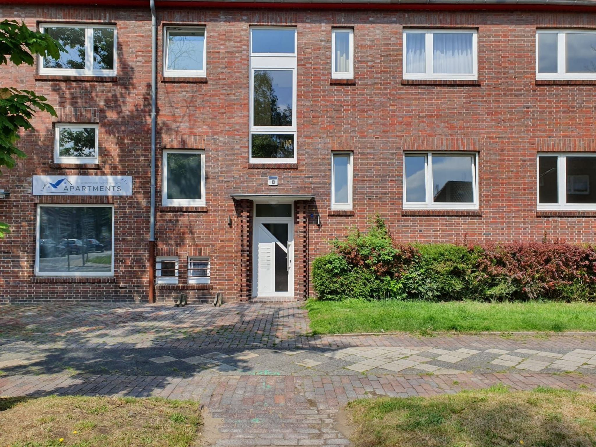A brick building with multiple windows and a sign indicating it is an apartment complex.