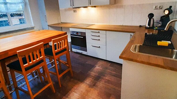 Une cuisine compacte avec une table et des chaises en bois, un four encastré et un évier.