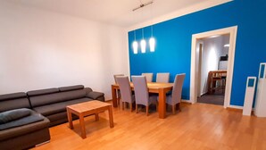 Un salon moderne avec un canapé foncé, une table basse en bois et un coin repas comprenant une table et des chaises.