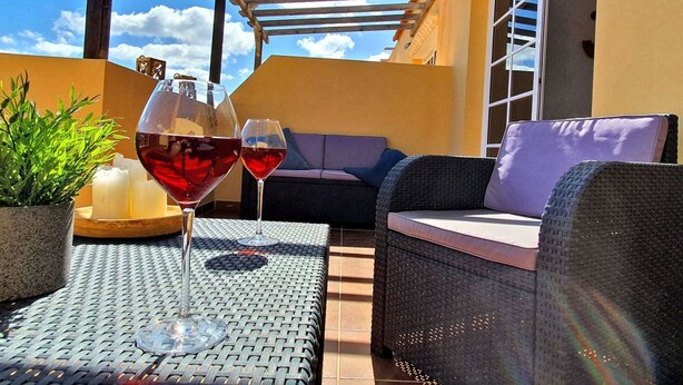 An outdoor patio with wicker furniture, two wine glasses, and a potted plant. - Casa Cristof by Interhome (Costa Calma)
