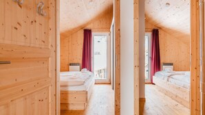 Une cabane en bois avec deux chambres, chacune comprenant un lit et une fenêtre.
