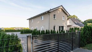 Una casa moderna de dos pisos con entrada pavimentada y puerta de metal.