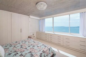 A bedroom with a bed, a dresser, and a view of the sea. - 3-bedroom Luxury Apartment in Cartagena with AC on the Beach (Cartagena de Indias)