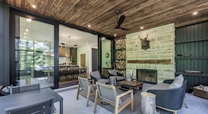 A modern outdoor living area with a fireplace, seating, and a view of the forest. - 7 bed 7 bath cottage on Lake Joseph (Parry Sound)