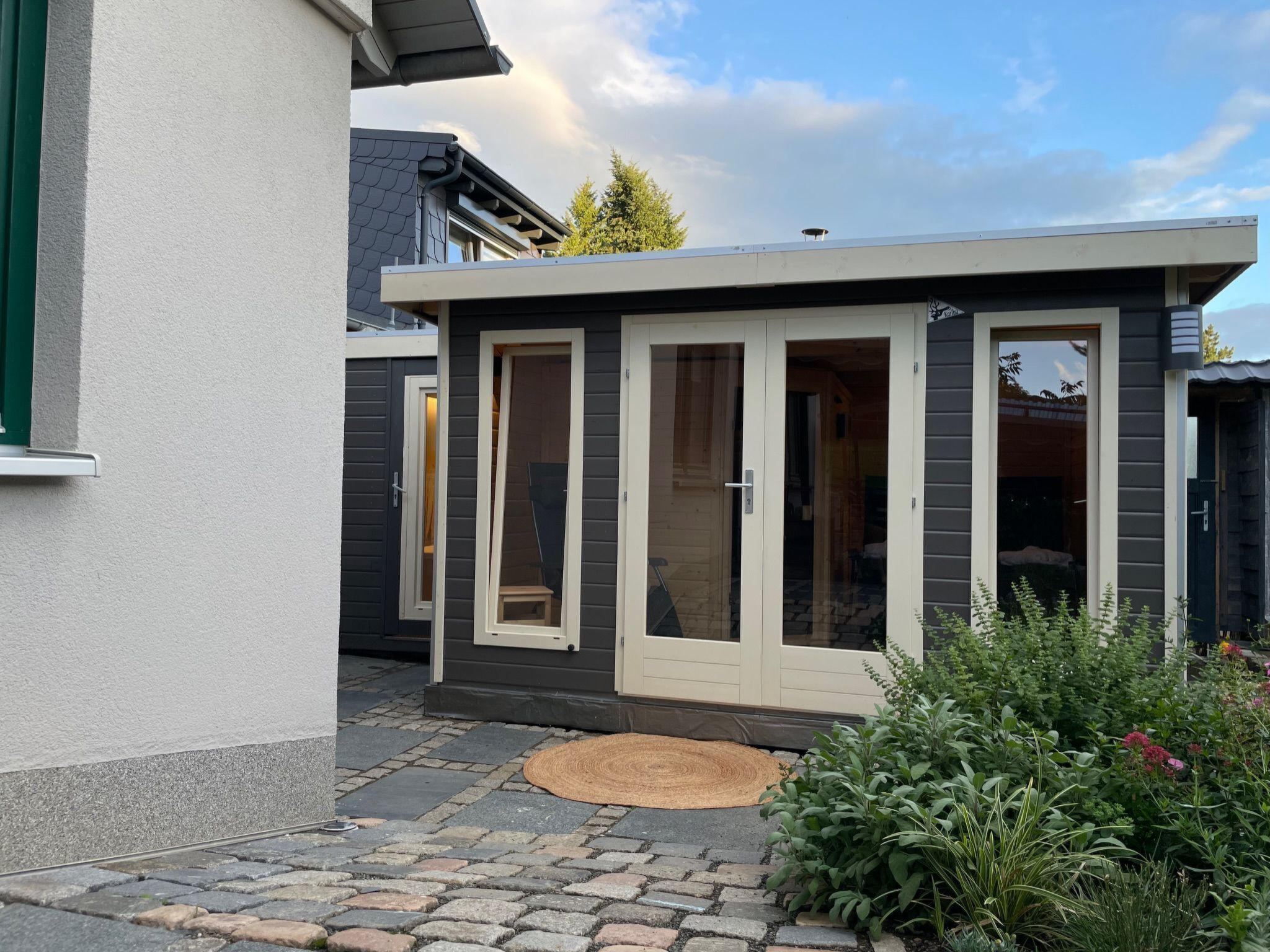 A modern house with a small attached garage, a covered patio, and a garden area.