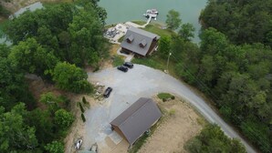Vue aérienne d’une propriété comprenant un grand bâtiment, un espace de stationnement et une jetée s’avançant dans un lac.