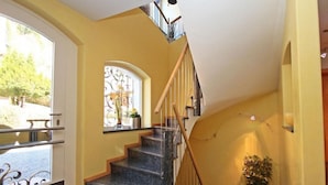 Eine Treppe mit einer Holzhandläufe und schwarzen Stufen, die zu einer zweiten Etage führt.