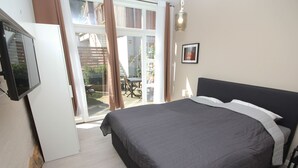 A bedroom with a bed, a TV, a sliding glass door to a patio, and a framed picture on the wall. - Wohnung in Bad Segeberg mit Terrasse by Interhome (Bad Segeberg)