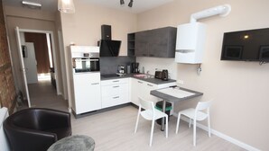 A modern kitchen with white cabinets, a built-in oven, a coffee machine, and a dining area with a table and chairs. - Wohnung in Bad Segeberg mit Terrasse by Interhome (Bad Segeberg)
