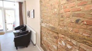 A modern interior with a brick wall, a radiator, a black armchair, and a small table. - Wohnung in Bad Segeberg mit Terrasse by Interhome (Bad Segeberg)