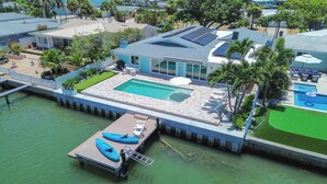 A waterfront property with a swimming pool, dock, and boat. - Waterfront 4 BR Home, Pool, Private Dock, Kayaks, Putting Green, Walk to Beach (Indian Rocks Beach)