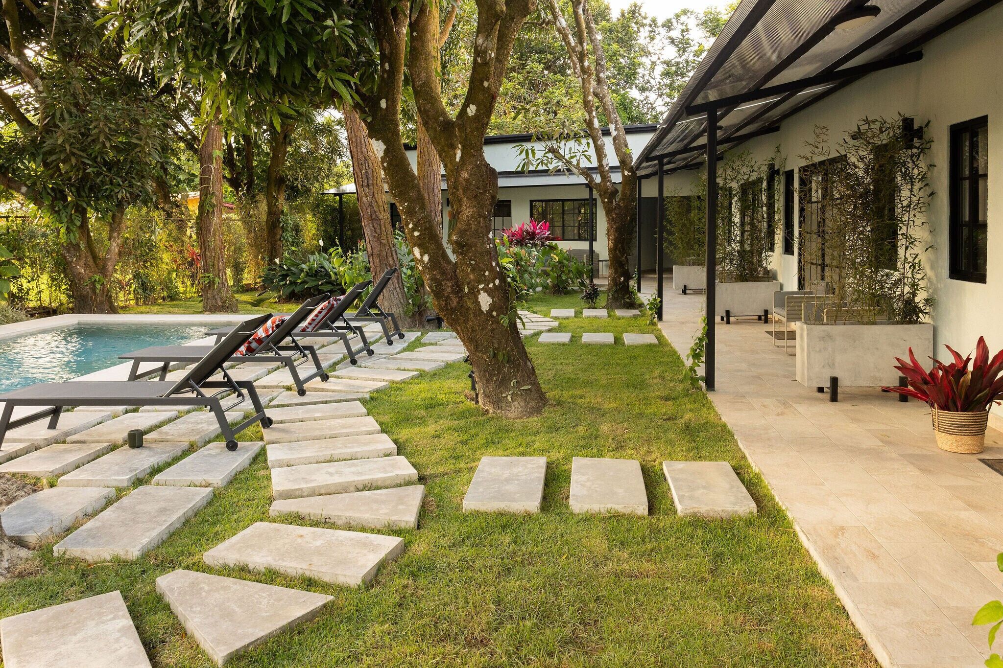 A modern outdoor area with a pool, stone steps, and lounge chairs.