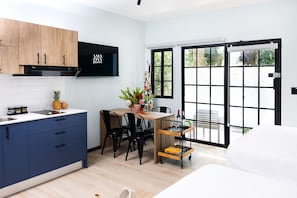 Une cuisine moderne avec des meubles en bois, un four encastré et un coin repas comprenant une table et des chaises.