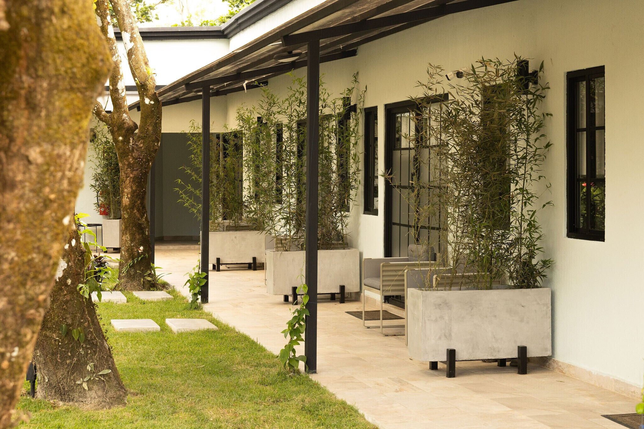 A covered outdoor area with concrete planters, seating, and a tree.