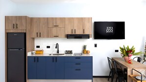 Eine moderne Küche mit Holzschränken, einem schwarzen Kühlschrank, einem Einbauofen, einer Spüle und einem Essbereich mit Tisch und Stühlen.