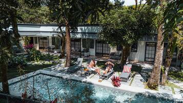 Un espace aménagé au bord de la piscine, avec des chaises longues, une piscine et un bâtiment doté de grandes fenêtres et d’une enseigne portant le chiffre « 3 ».