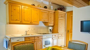 A kitchen with wooden cabinets, a stove, and a dining table with chairs. - Apartment Heaven by Interhome (Gaschurn)