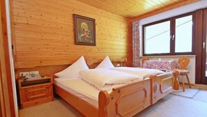A wooden-paneled bedroom with a bed, a nightstand, a chair, and a window. - Apartment Heaven by Interhome (Gaschurn)