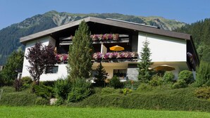 A two-story building with balconies adorned with flowers, set against a mountainous backdrop. - Apartment Heaven by Interhome (Gaschurn)