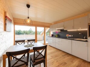 Eine moderne Küche mit Holzausstattung, einem Esstisch mit Stühlen und einer Pendelleuchte.