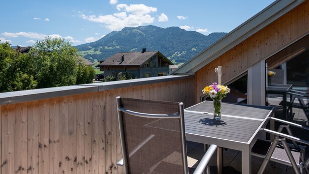 A balcony with a table and chair, overlooking a mountainous landscape with houses. - Ruhig mit einem herrlichen Blick auf die Berge. by Interhome (Schwarzenberg)