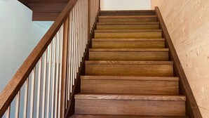 A wooden staircase with a railing, leading to an upper floor. - Ruhig mit einem herrlichen Blick auf die Berge. by Interhome (Schwarzenberg)