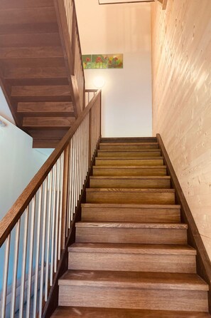 Eine Holztreppe mit Geländer, die zu einer oberen Etage führt.