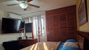 A bedroom with a bed, a TV mounted on the wall, a ceiling fan, and a wardrobe. - MINISUITE with river view (Boca del Río)