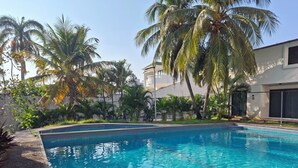 A swimming pool surrounded by palm trees and a building with a white exterior. - MINISUITE with river view (Boca del Río)
