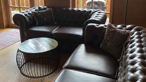 Ein gemütliches Wohnzimmer mit einer Eckcouch, einem runden Couchtisch und einem Kamin.