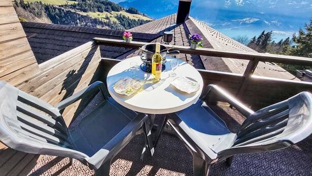En terrasse med et bord og stole med udsigt over et bjerglandskab.
