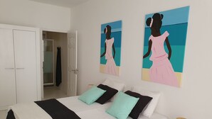 Une chambre à coucher comprenant un lit, deux oreillers, une table de chevet avec une lampe et deux œuvres d’art murales.