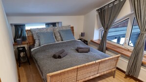 Una camera da letto con un letto grande, due comodini, una finestra con tende e vista all'esterno.