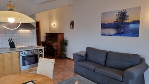 Una cucina moderna con zona pranzo, un divano grigio e un quadro che raffigura un paesaggio invernale.