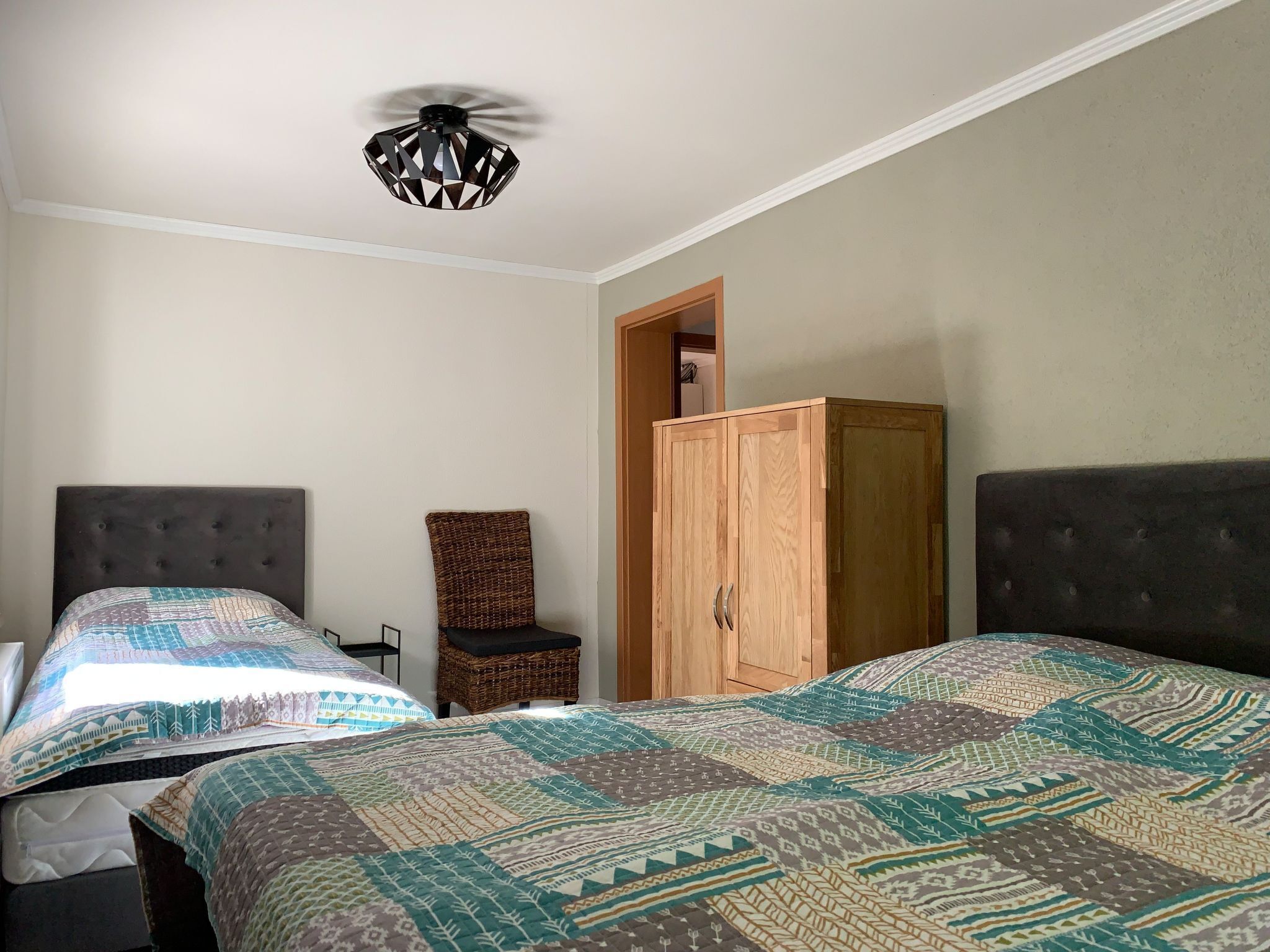 Ein Schlafzimmer mit zwei Betten, einem Deckenventilator, einem Kleiderschrank und einem Sessel.
