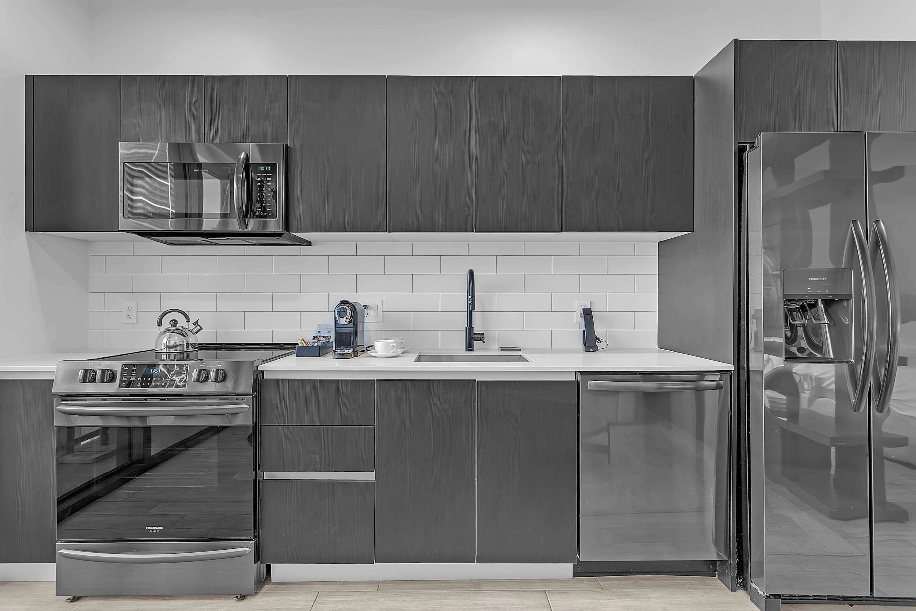 A modern kitchen with stainless steel appliances, a microwave, oven, and refrigerator.