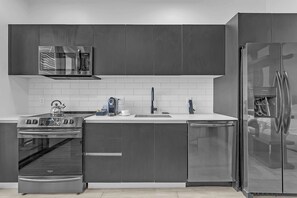 Eine moderne Küche mit Edelstahlgeräten, einer Mikrowelle, einem Backofen und einem Kühlschrank.