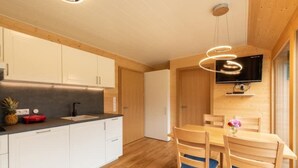 A modern kitchen with white cabinets, a black countertop, and a wooden dining table with blue cushions. - Neue Ferienwohnung in Schwarzenberg mit Garten und Grill by Interhome (Schwarzenberg)