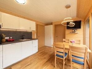 A modern kitchen with white cabinets, a black countertop, and a wooden dining table with blue cushions. - Neue Ferienwohnung in Schwarzenberg mit Garten und Grill by Interhome (Schwarzenberg)
