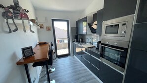 Une cuisine moderne avec une table en bois, un four encastré et un four à micro-ondes.