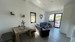 Un vaste espace de vie comprenant une table à manger en bois, un canapé et une grande fenêtre donnant sur l’extérieur.