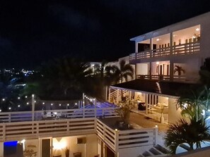 Ein zweistöckiges Gebäude mit Balkon und Außenbereich, umgeben von Palmen.