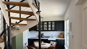 Een moderne keuken met een trap, zwarte kasten en een ronde eettafel met stoelen.